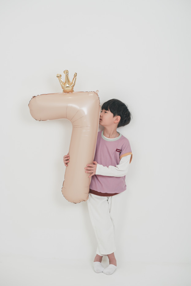 숫자 7 풍선을 안고 있는 아이의 생일 사진