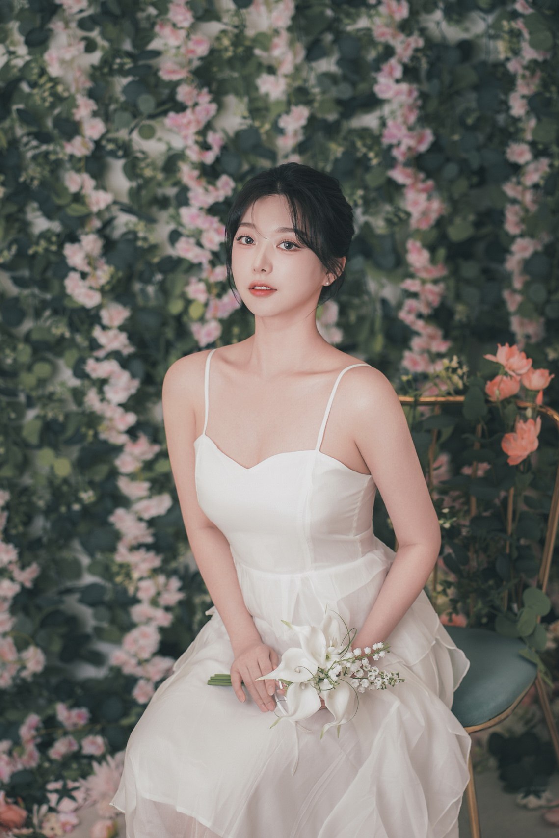 꽃 배경 앞에서 부케를 들고 앉은 인물 사진